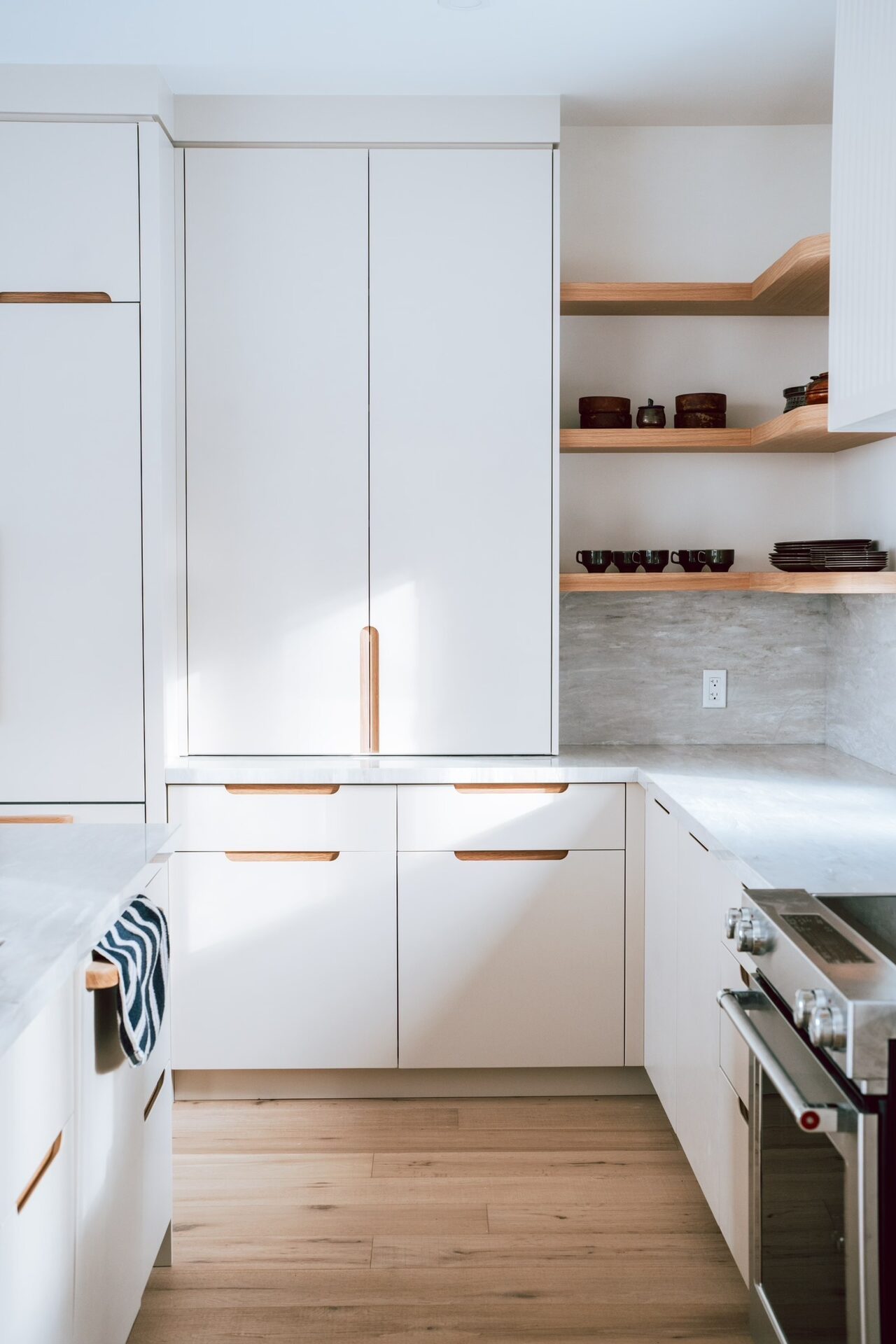 White kitchen with handcrafted wood pulls and floating shelves